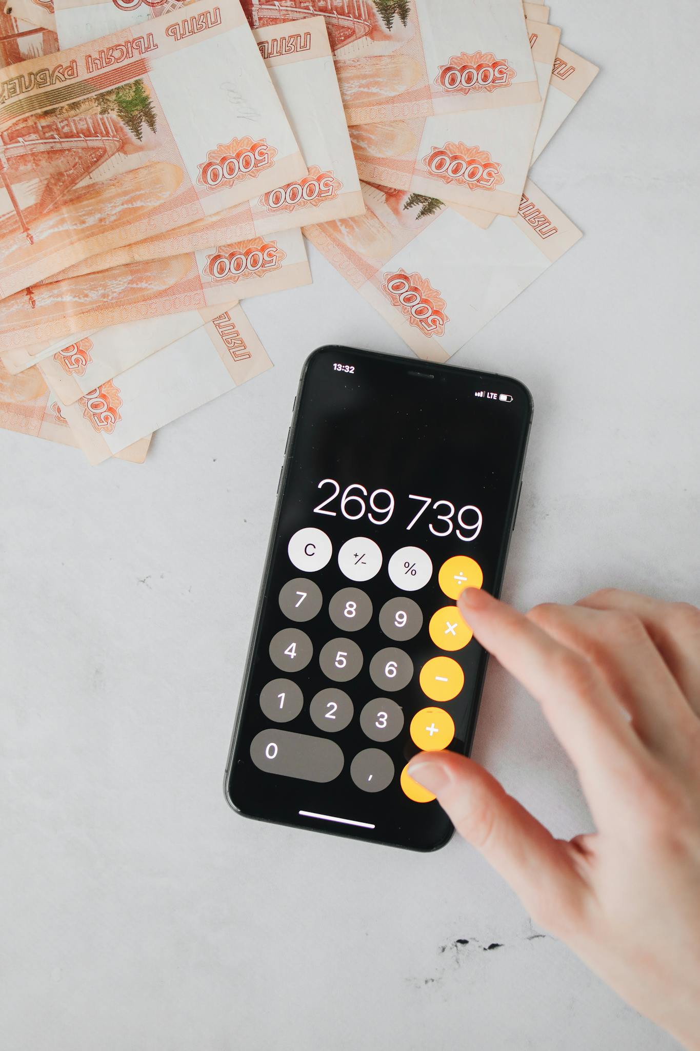 Close-up of smartphone calculator and ruble banknotes, illustrating financial calculations.